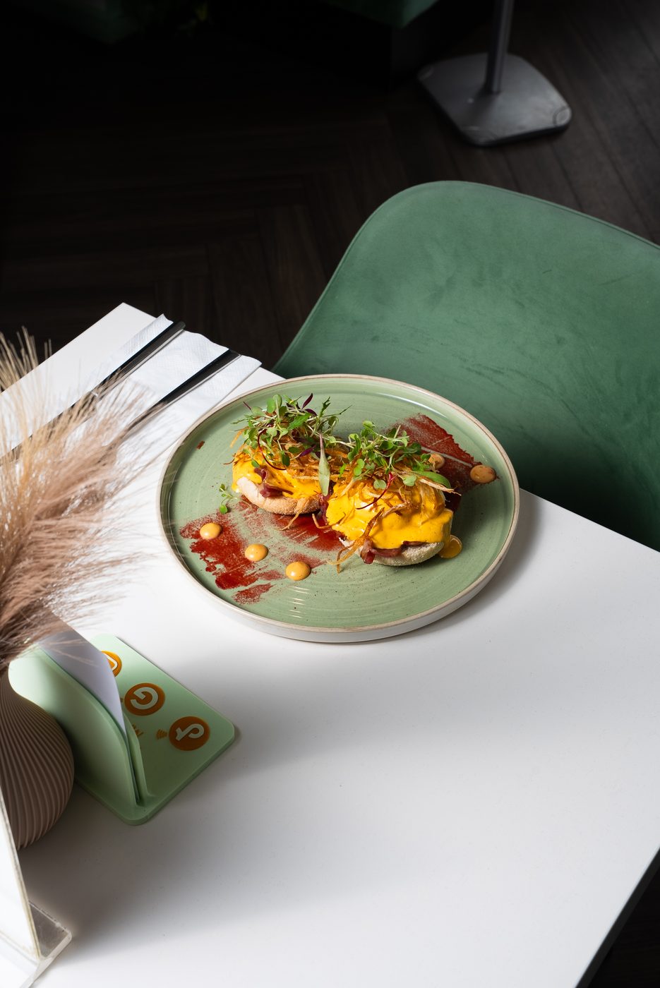 Eggs benedict with crispy onions on a green plate