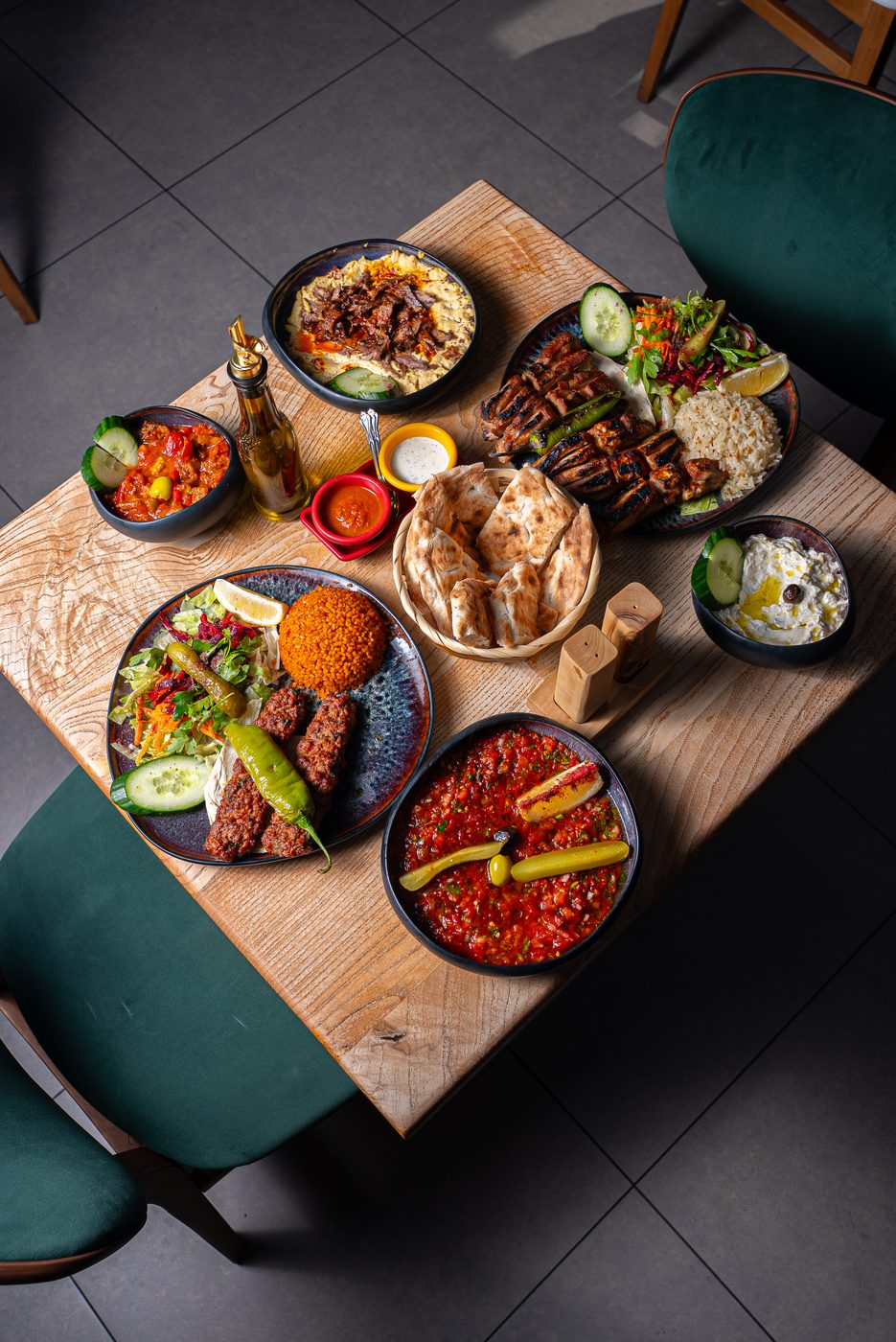 Overhead spread of grilled meats, dips, and flatbread