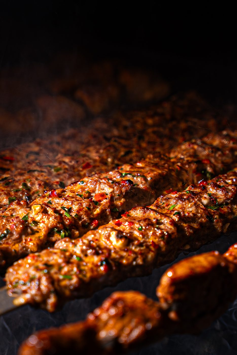 Skewers of kebab grilling with smoke and char