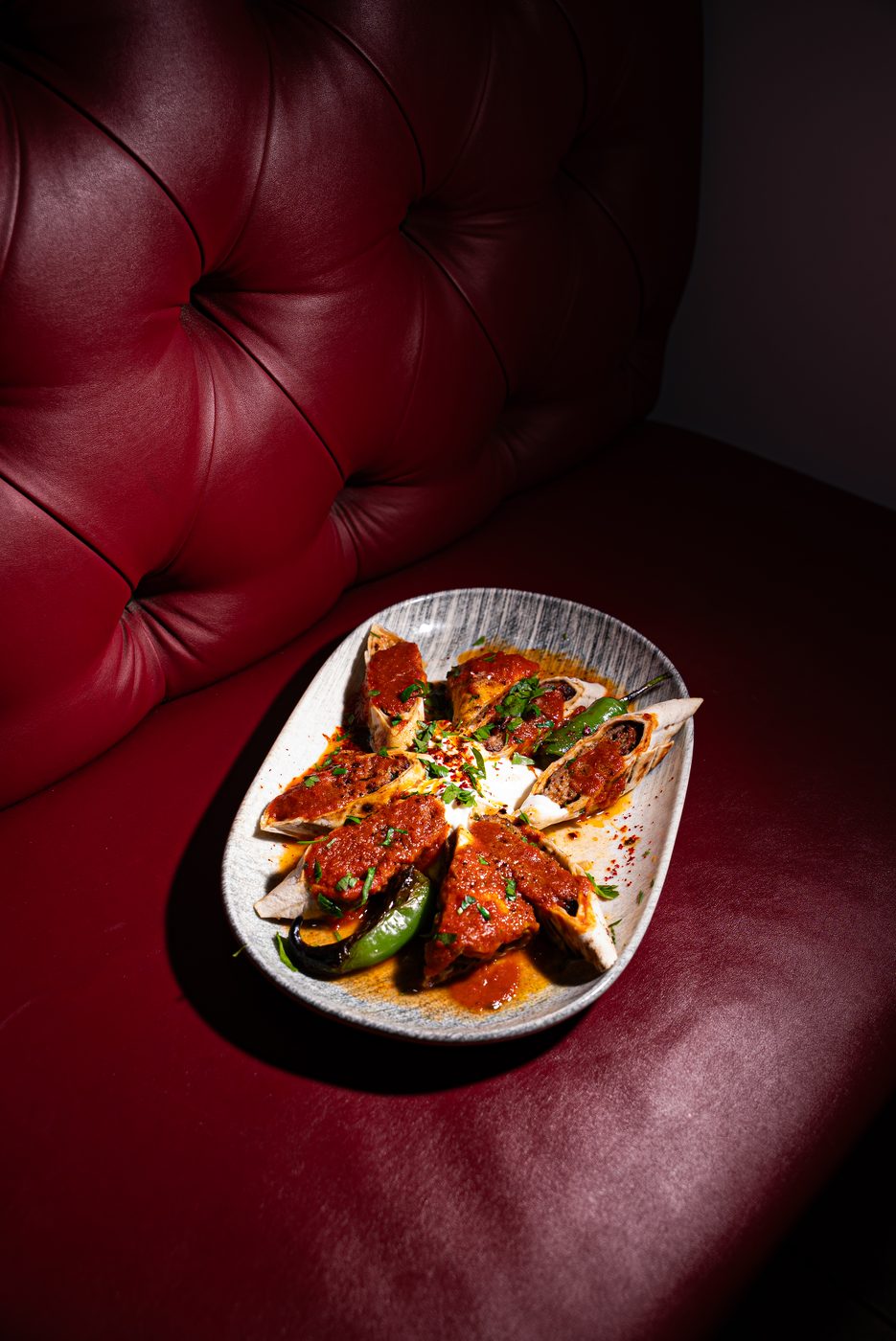 Stuffed wraps with tomato sauce on a red leather booth